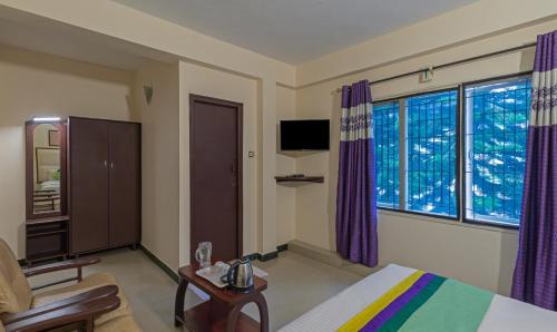 a hotel room with a bed and a chair and windows at Treebo Kodai Kings Park, 650 M From Kodai Lake in Kodaikānāl