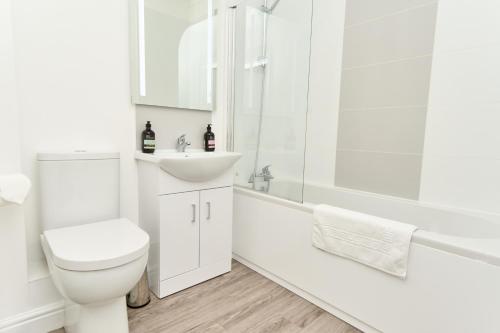 Baño blanco con aseo y lavamanos en Beautiful 3 Bed Apartment - Large Outside Terrace & Parking - The Perfect Choice For Families, Small Groups & Contractors - Close To Ventnor Beach, en Ventnor