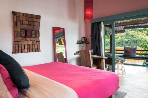 a bedroom with a pink bed and a mirror at Ock Pop Tok Mekong Villa in Luang Prabang