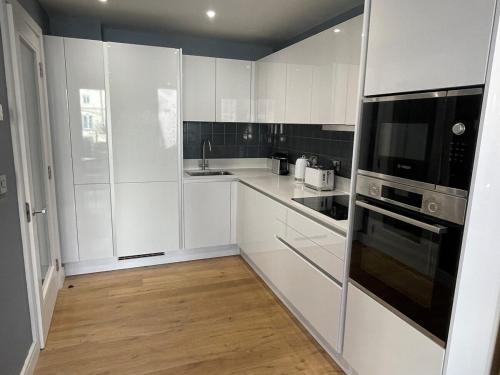 a kitchen with white cabinets and a black appliance at Harbourside Hideaway - Superb Flat with Terrace in Bristol