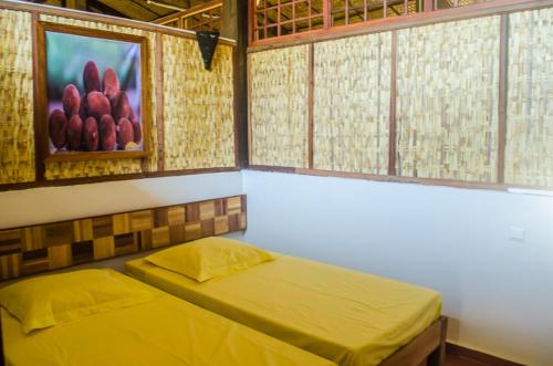 - une chambre avec 2 lits et un tableau mural dans l'établissement Espace Menamasoandro, à Morondava