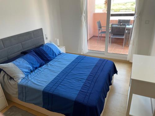 een bed met blauwe lakens in een kamer met een balkon bij Condado De Alhama in Murcia