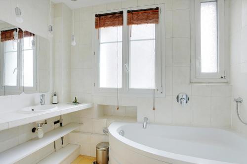 Baño blanco con bañera y 2 lavabos en Pick A Flat's Apartment in Saint-Ouen - Rue des Rosiers, en Saint-Ouen