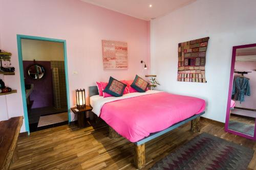 a bedroom with a pink bed and a mirror at Ock Pop Tok Mekong Villa in Luang Prabang