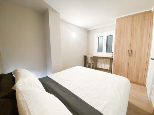 a bedroom with a white bed and a wooden cabinet at ¡Más céntrico imposible! 6PAX+PK in Andorra la Vella
