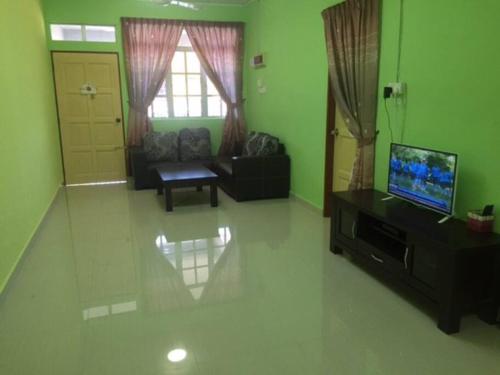 a living room with green walls and a flat screen tv at D'FIEZA HOMESTAY KEMAMAN in Cukai