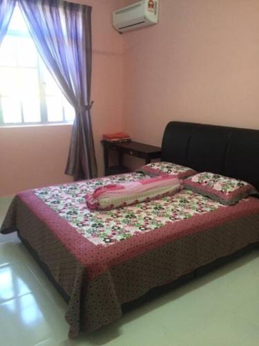 a bed in a room with a bedspread with flowers on it at D'FIEZA HOMESTAY KEMAMAN in Cukai
