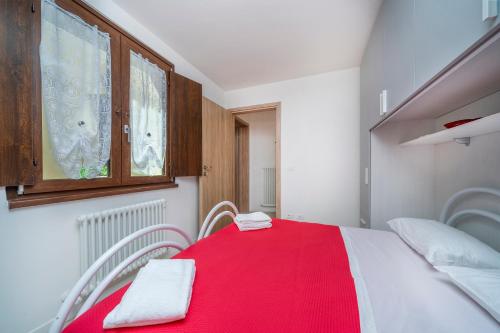 Un pequeño dormitorio con una manta roja en una cama en Residenza alle Grazie, en Udine