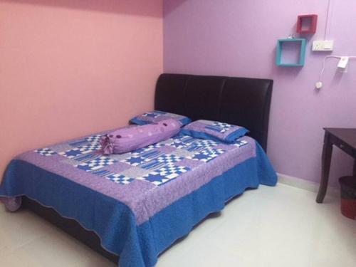 a small bedroom with a bed with a purple wall at D'FIEZA HOMESTAY KEMAMAN in Cukai