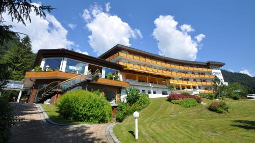 a large building with glass windows on a hill at Alpenhotel Oberstdorf - ein Rovell Hotel in Oberstdorf