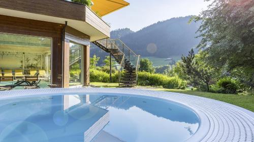 a swimming pool in front of a house at Alpenhotel Oberstdorf - ein Rovell Hotel in Oberstdorf