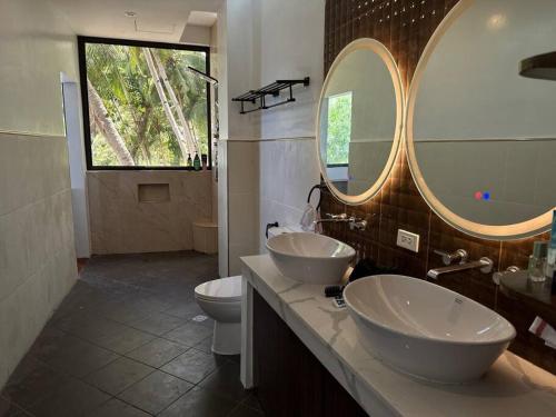 a bathroom with two sinks and a toilet and two mirrors at The French Villa -Santander in Santander