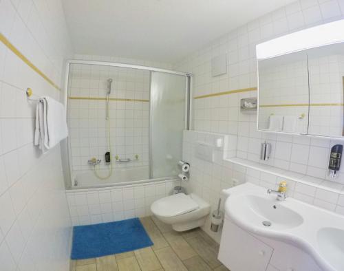 a white bathroom with a toilet and a sink at Haus Adora in Leukerbad