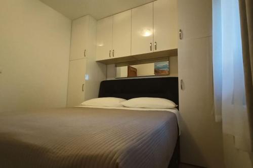 a bedroom with a large bed with white cabinets at Apartmani Srdarović 3 in Drage