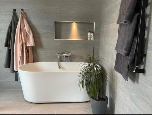a white tub in a bathroom with a potted plant at New luxurious Villa in Helsingborg close to the City in Helsingborg