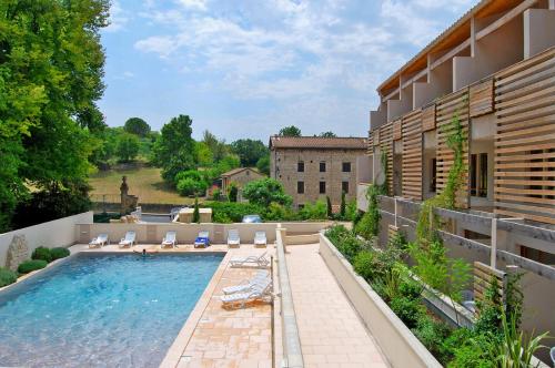 a swimming pool with lounge chairs and a building at Lagrange Grand Bleu Vacances – Résidence La Closerie in Barjac