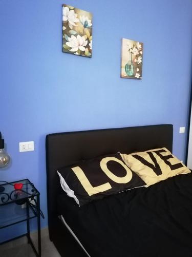 a bedroom with a blue wall and a bed with the word love at Bed&Dreams in Salento - Bilocale deluxe con vasca idromassaggio in Guagnano