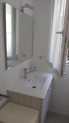 a white bathroom with a sink and a mirror at Casa Le Cementine in Verbania