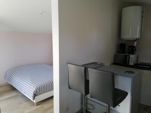 a room with a desk with a microwave and a bed at Studio privé in Saint-Aignan-Grand-Lieu