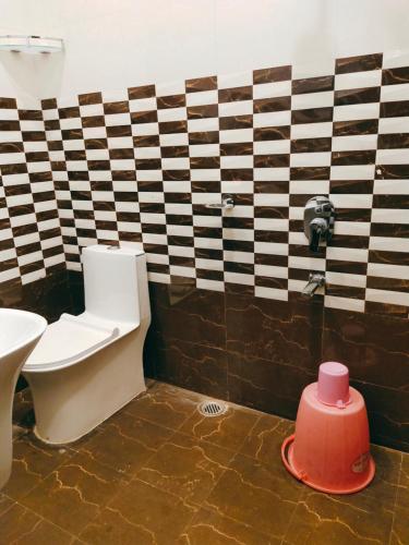 a bathroom with a toilet and a pink cylinder on the floor at Hotel The Shree Jee Palace in Mirzāpur