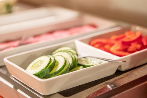 two white dishes with cucumbers and peppers on a counter at Hotel Kupolen in Borlänge