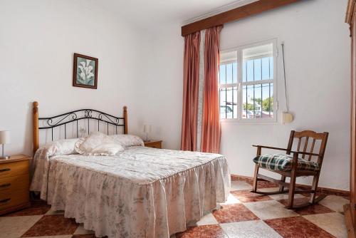 a bedroom with a bed and a chair and a window at Villa Juana in Conil de la Frontera