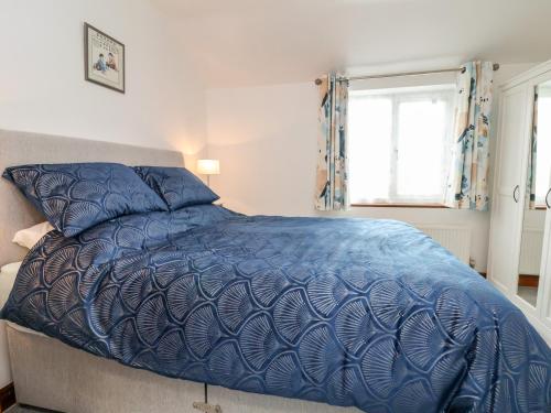 uma cama com um edredão azul num quarto em 91 Main Street em Frodsham