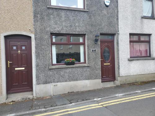 dos puertas marrones en el lateral de un edificio en Beautiful 2-Bed House in Larne with free parking, en Larne