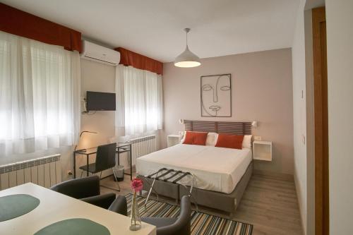 una camera con letto, scrivania e tavolo di Apartamentos Los Arroyos a Ponferrada