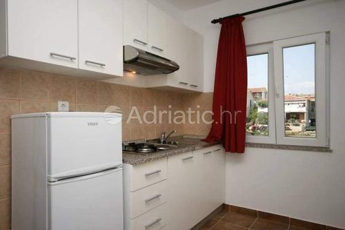a kitchen with a white refrigerator and a window at Apartments Zoran in Povljana