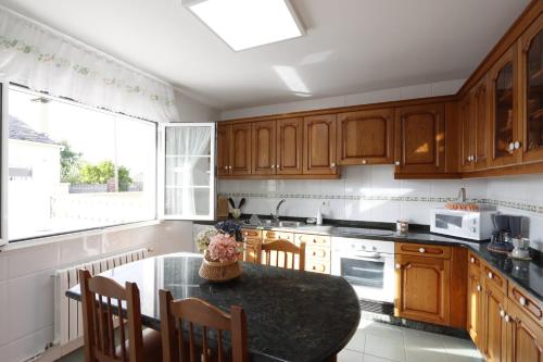una cucina con mobili in legno e un tavolo con sedie di Casa Flor Delfin Ribadeo a Ribadeo