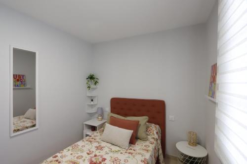 Dormitorio pequeño con cama y espejo en Casa Flor Delfin Ribadeo, en Ribadeo