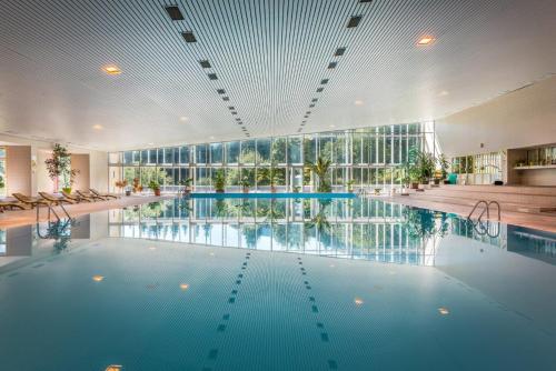 a large swimming pool in a building with a large window at Hotel SOREA MÁJ in Liptovský Ján