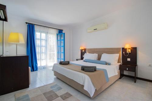 a bedroom with a large bed with blue curtains at Ladonia Hotels Zemda Gümüşlük in Gumusluk