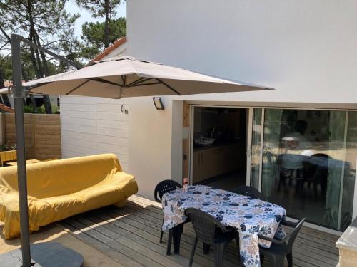 un patio avec une table et un parasol dans l'établissement APPARTEMENT studio CAPBRETON SANTOCHA, à Capbreton