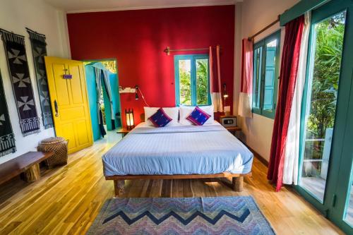 a bedroom with a bed with red walls and windows at Ock Pop Tok Mekong Villa in Luang Prabang