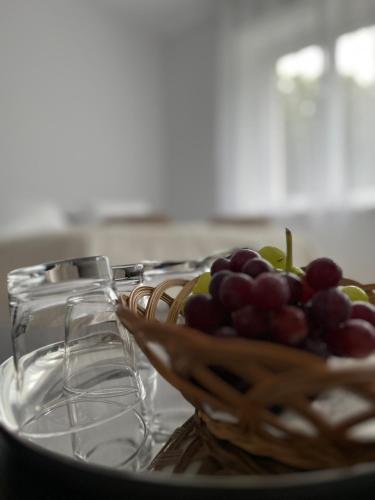 a bowl of grapes on a table with wine glasses at Apartament Pod Kamienną Górą II in Gdynia