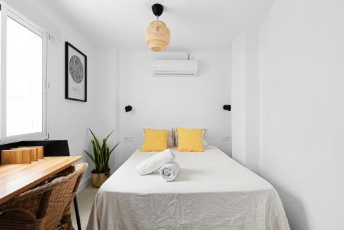 Dormitorio blanco con cama con almohadas amarillas en Pineapple Canasteros 7, en Málaga