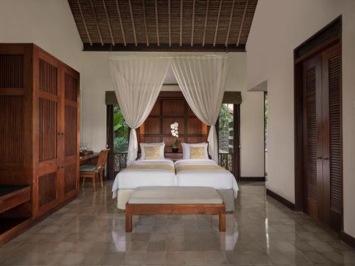 a bedroom with two beds and a table in it at Alila Ubud in Ubud