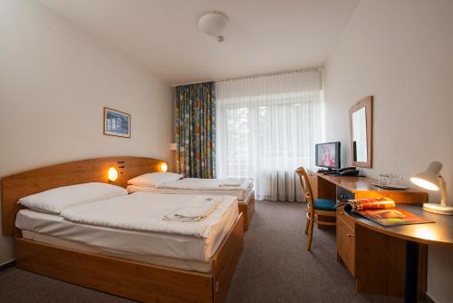 a hotel room with two beds and a desk with a computer at Hotel SOREA MÁJ in Liptovský Ján