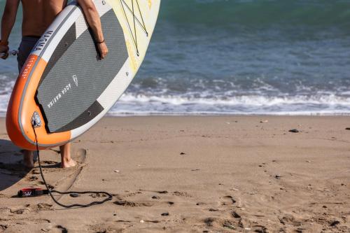 a man is holding a surfboard on the beach at Casa Negro in Rethymno Town
