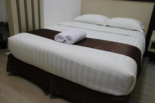 a bed with two rolled up towels on it at Dawala Hotel in Sudiang