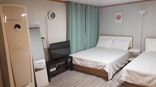 a small room with two beds and a television at Hangeul Guesthouse in Seoul