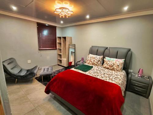 1 dormitorio con 1 cama con manta roja y silla en Parys In town Guest lodge and Conference Center, en Parys
