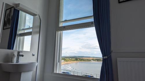 a bathroom with a window with a view of a beach at Areawest in Scarborough