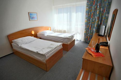 a hotel room with two beds and a desk at Hotel SOREA MÁJ in Liptovský Ján