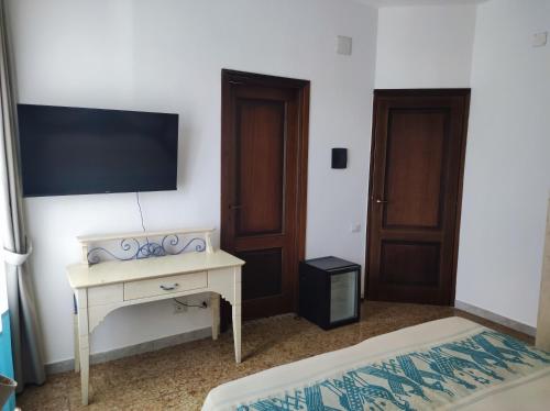 a bedroom with a desk and a tv on the wall at San Raffaele Guest House in Villasimius