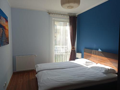 a blue bedroom with a bed and a window at Apartament Oliver in Darlowko