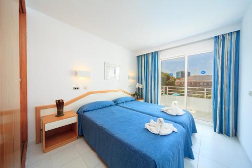 a bedroom with a blue bed and a large window at Apartamento Via Alemanya Standard A in Can Picafort