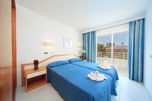 a bedroom with a blue bed and a large window at Apartamento Via Alemanya Standard C in Can Picafort